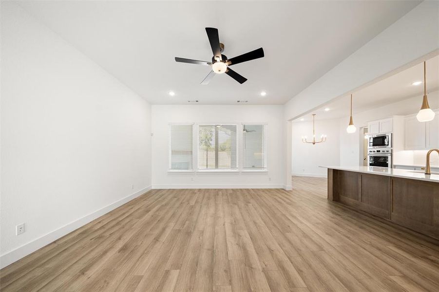 Unfurnished living room with light wood-style floors, a chandelier, recessed lighting, and ceiling fan
