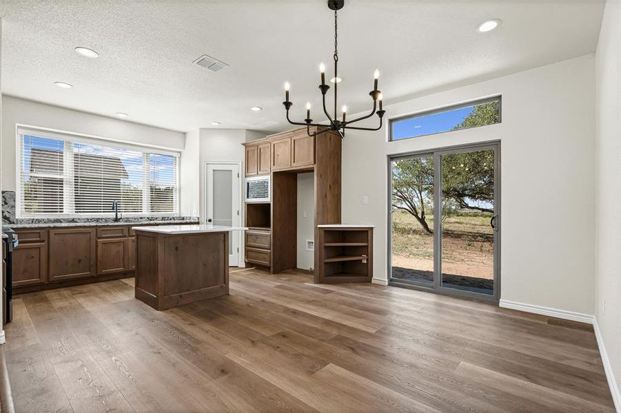 Kitchen featuring a chandelier, a kitchen island, decorative light fixtures, dark wood-type flooring, and recessed lighting