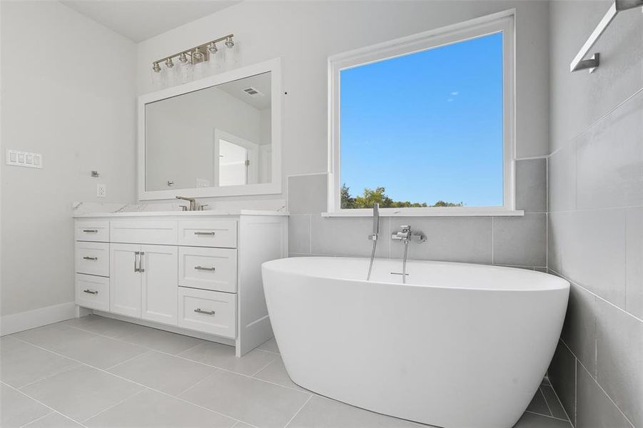 Bathroom with vanity, a freestanding tub, and light tile patterned floors Bathroom with vanity, a freestanding tub, and light tile patterned floors