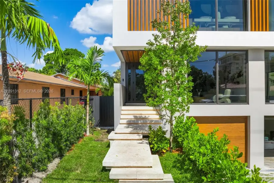 Modern architectural exterior featuring smooth white stucco finish, wood-slat cladding, expansive floor-to-ceiling glass windows, stone-paved floating staircase, and wood-paneled garage door Modern architectural exterior featuring smooth white stucco finish, wood-slat cladding, expansive floor-to-ceiling glass windows, stone-paved floating staircase, and wood-paneled garage door