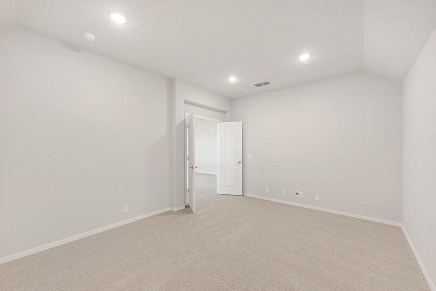 Empty bedroom with beige carpet, white walls, recessed lighting, and open door to hallway Empty bedroom with beige carpet, white walls, recessed lighting, and open door to hallway