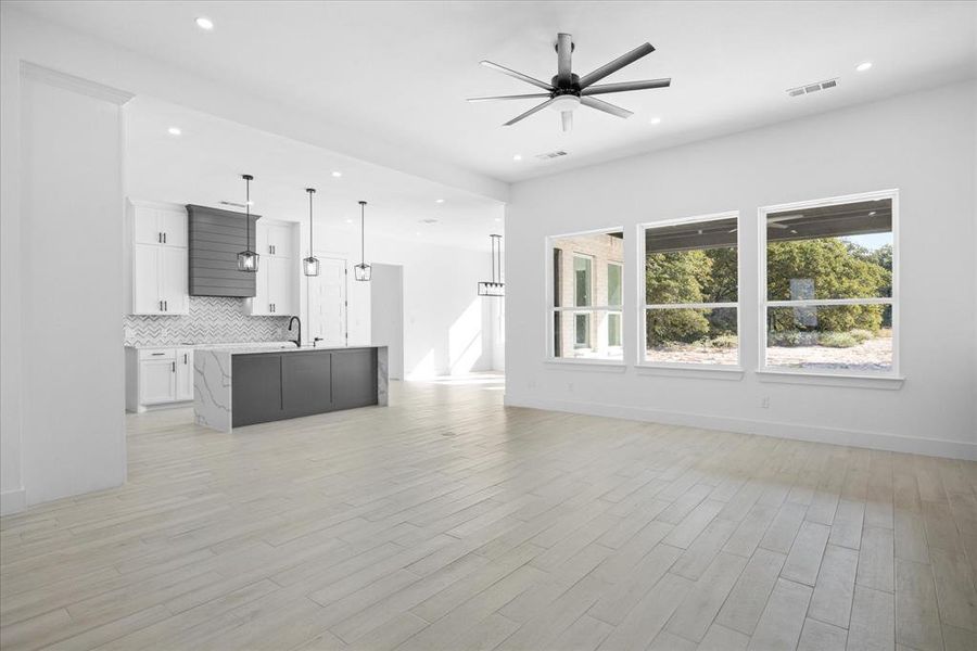 Open-concept interior featuring light Porcelain Tile-finish flooring, recessed lighting, and a contemporary ceiling fan. Well lighted Living room, Kitchen and Dining area