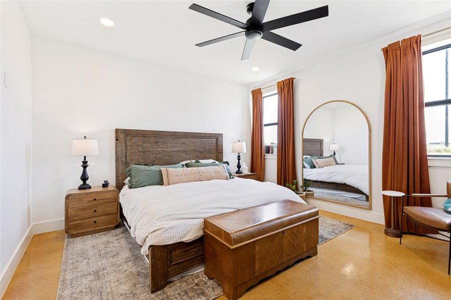 Spacious bedroom featuring light-toned flooring, tall windows, and a ceiling fan Spacious bedroom featuring light-toned flooring, tall windows, and a ceiling fan