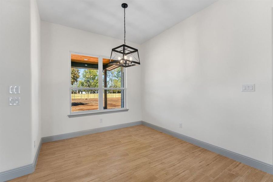 Unfurnished dining area with light wood-type flooring and a chandelier