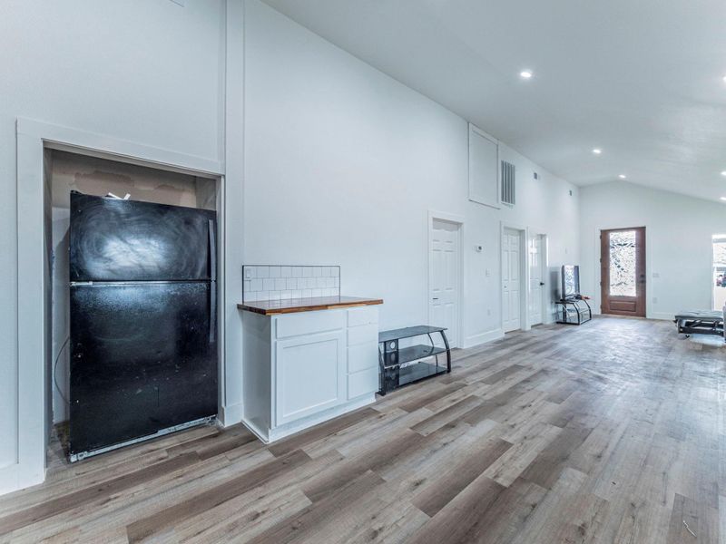Unfurnished living room with lofted ceiling, light wood-type flooring, and recessed lighting