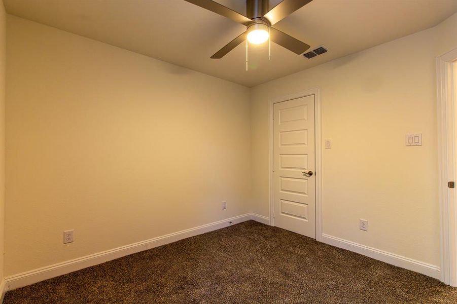 Unfurnished room featuring dark carpet and ceiling fan Unfurnished room featuring dark carpet and ceiling fan