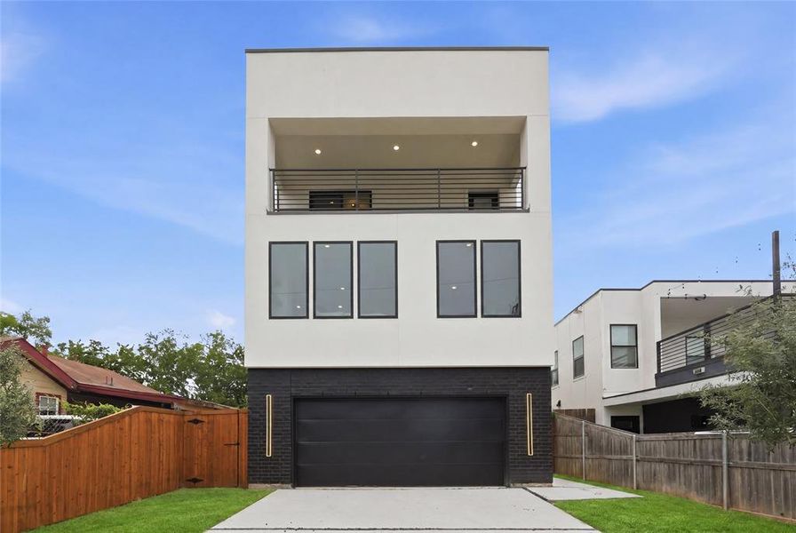 Contemporary three-story residence featuring a white stucco facade and a black brick lower level Contemporary three-story residence featuring a white stucco facade and a black brick lower level