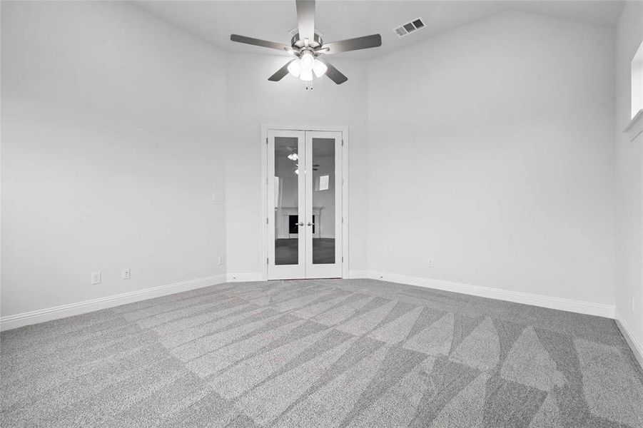 Carpeted spare room with visible vents, lofted ceiling, baseboards, french doors, and a ceiling fan