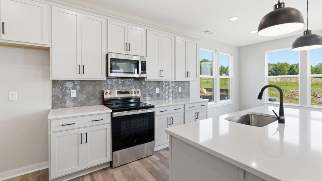 Kitchen with tile backsplash, pendant lighting, and quartz countertops Kitchen with tile backsplash, pendant lighting, and quartz countertops