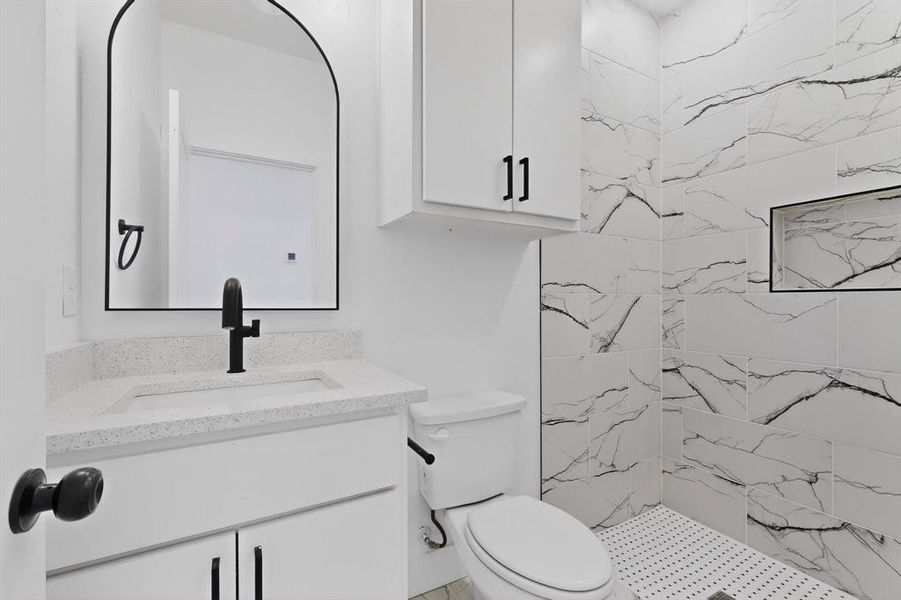 Full bath featuring vanity and a marble finish shower