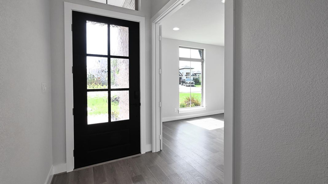 Foyer entrance with a textured wall, wood finished floors, and recessed lighting