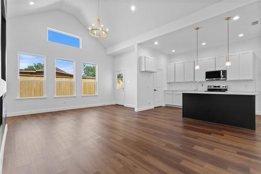 Unfurnished living room with dark wood-style floors, high vaulted ceiling, recessed lighting, and a chandelier Unfurnished living room with dark wood-style floors, high vaulted ceiling, recessed lighting, and a chandelier