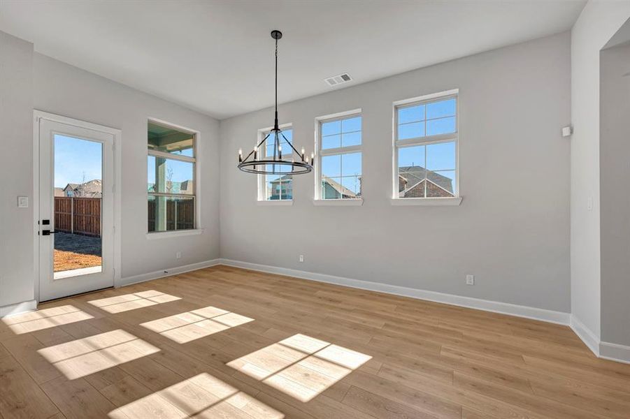 Unfurnished dining area featuring plenty of natural light, a chandelier, and light wood-style flooring