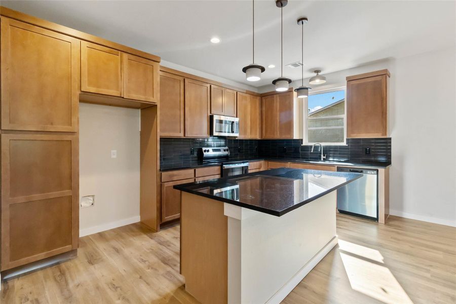 Kitchen with backsplash, appliances with stainless steel finishes, light wood-style flooring, and recessed lighting