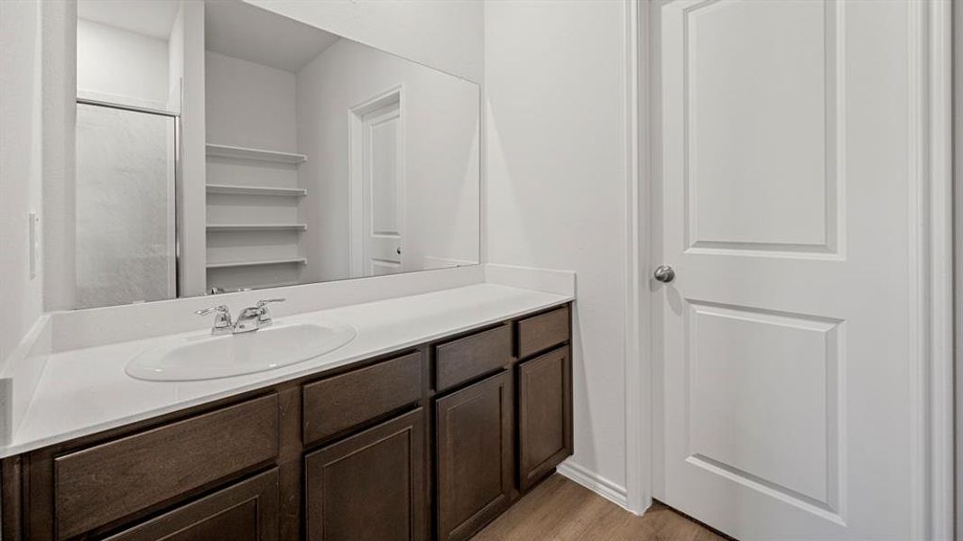 Full bath with a shower stall, vanity, and light wood-style flooring