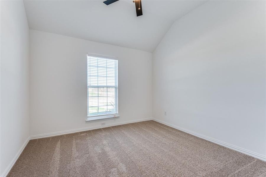 Carpeted spare room with ceiling fan and vaulted ceiling