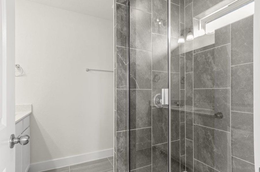 A well-appointed bathroom features a spacious glass-enclosed shower and a modern vanity.