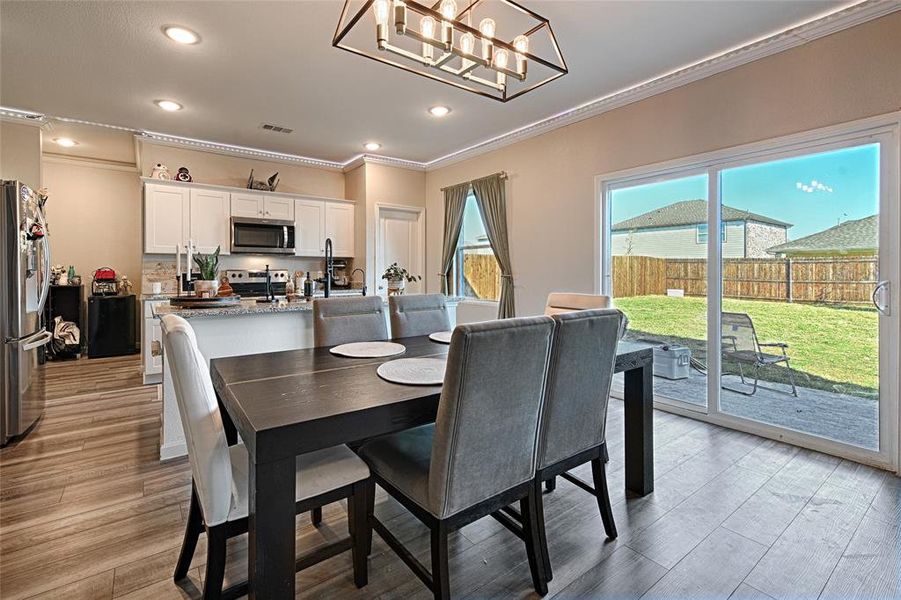 Dining space with ornamental molding, light wood-style flooring, a chandelier, and recessed lighting Dining space with ornamental molding, light wood-style flooring, a chandelier, and recessed lighting
