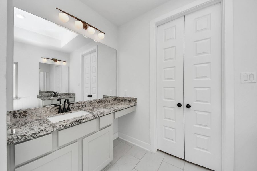 This bathroom features a sleek design with a large mirror, granite countertop, and under-mount sink. It has modern light fixtures and a double-door closet, all set against a bright, neutral color scheme. This bathroom features a sleek design with a large mirror, granite countertop, and under-mount sink. It has modern light fixtures and a double-door closet, all set against a bright, neutral color scheme.
