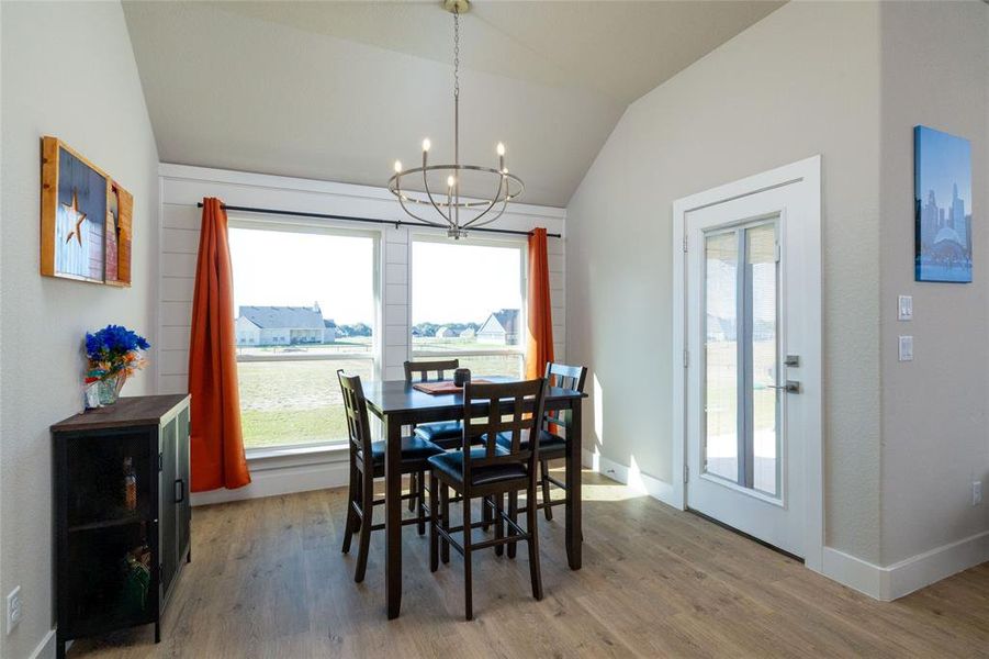 Dining space with light wood-style flooring, lofted ceiling, and a chandelier