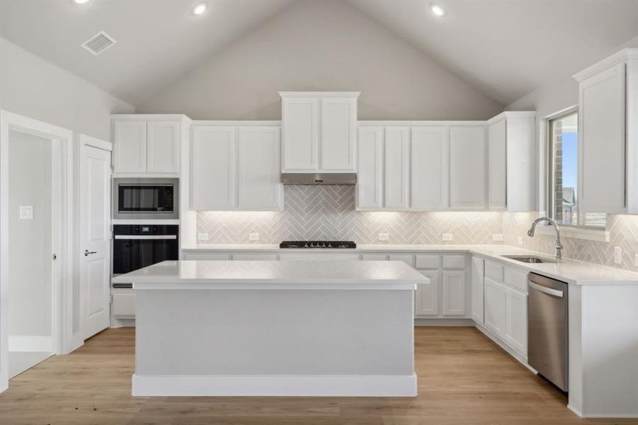 Kitchen with dishwasher, oven, built in microwave, a kitchen island, and white cabinetry