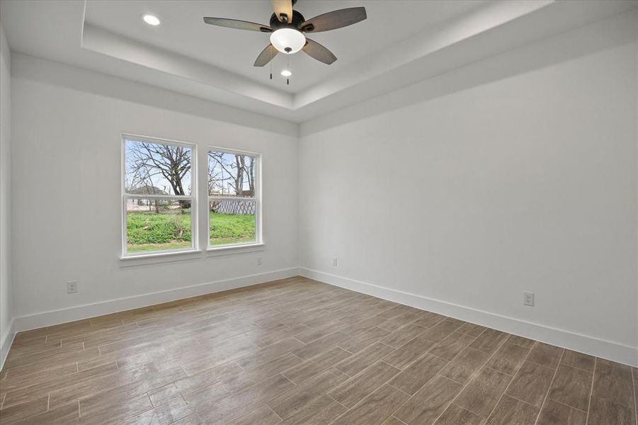 Empty room with wood tiled floors, ceiling fan, recessed lighting, and a tray ceiling