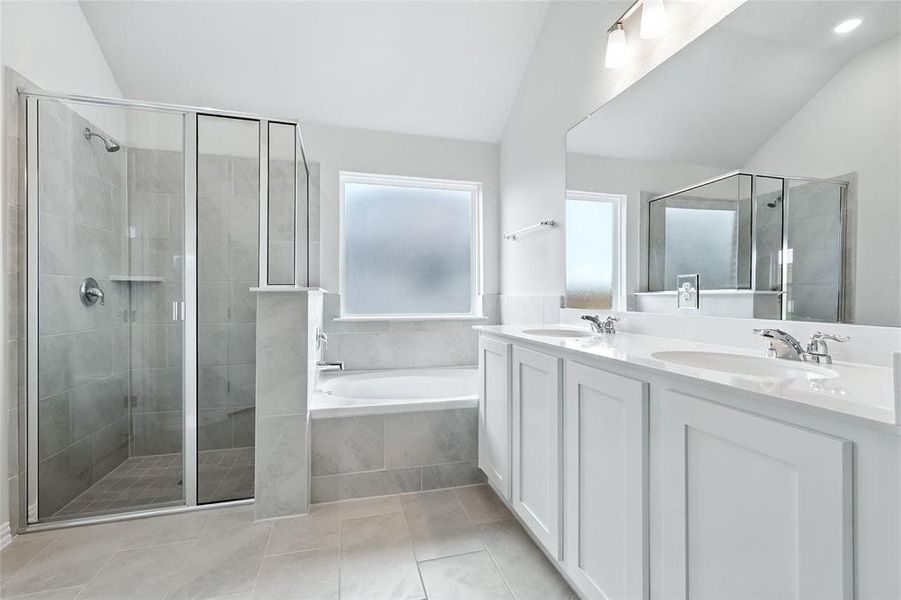 Full bath with lofted ceiling, double vanity, a shower stall, a bath, and tile patterned flooring