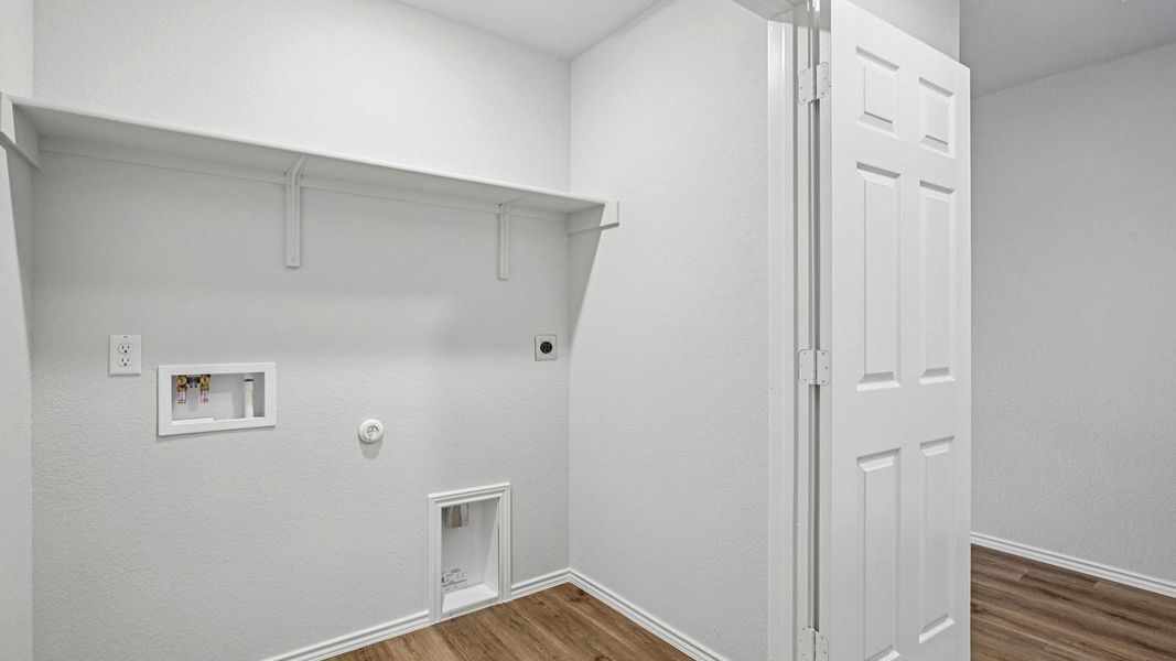 Functional laundry room featuring a built-in shelf and durable wood flooring.
