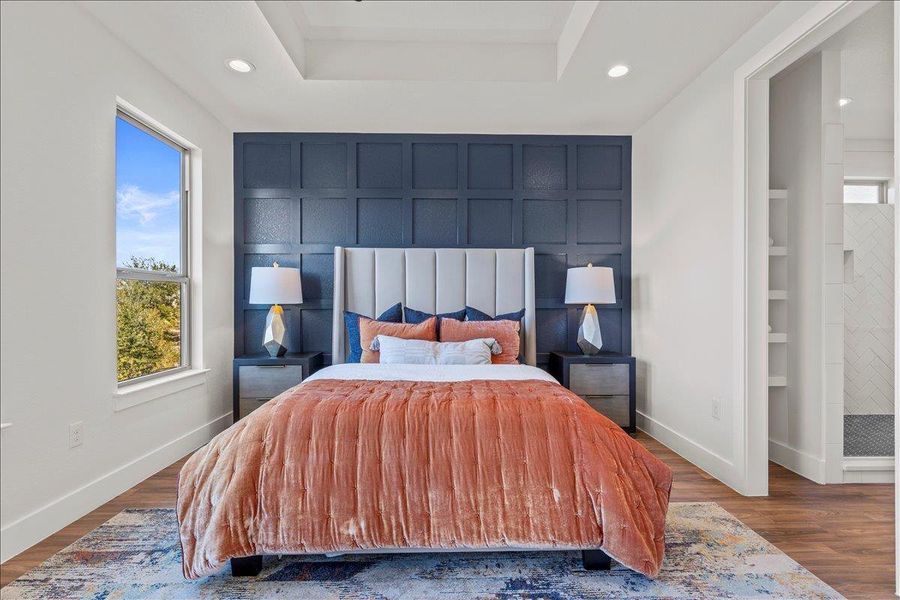 Bedroom featuring wood finished floors, a raised ceiling, recessed lighting, and connected bathroom