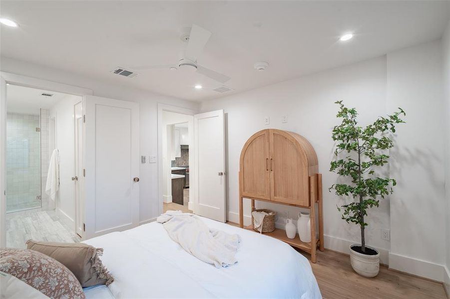 Bedroom featuring light hardwood floors, ensuite bath, and ceiling fan