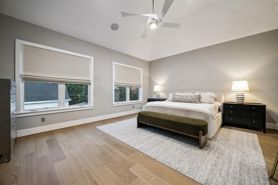 The spacious primary suite is a luxurious retreat, featuring expansive windows that bathe the room in natural light and create a bright, serene ambiance.