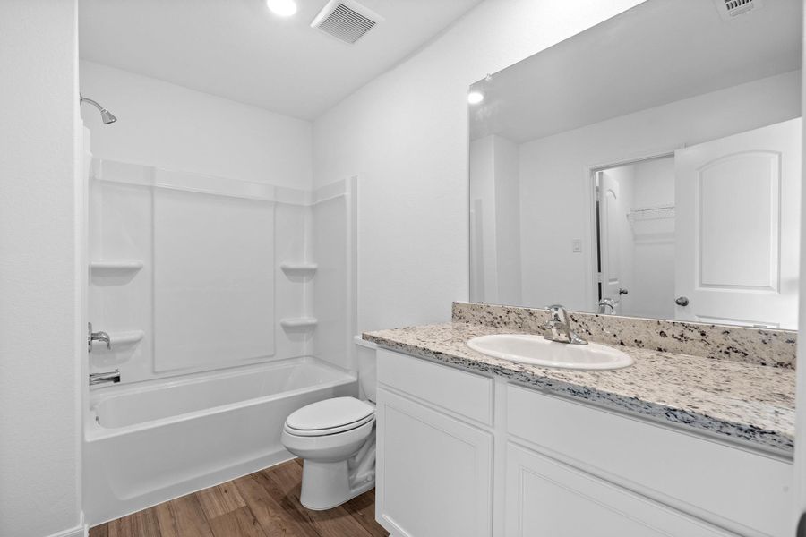 Full bathroom featuring shower / bath combination, vanity, dark wood-type flooring, a spacious closet, and recessed lighting