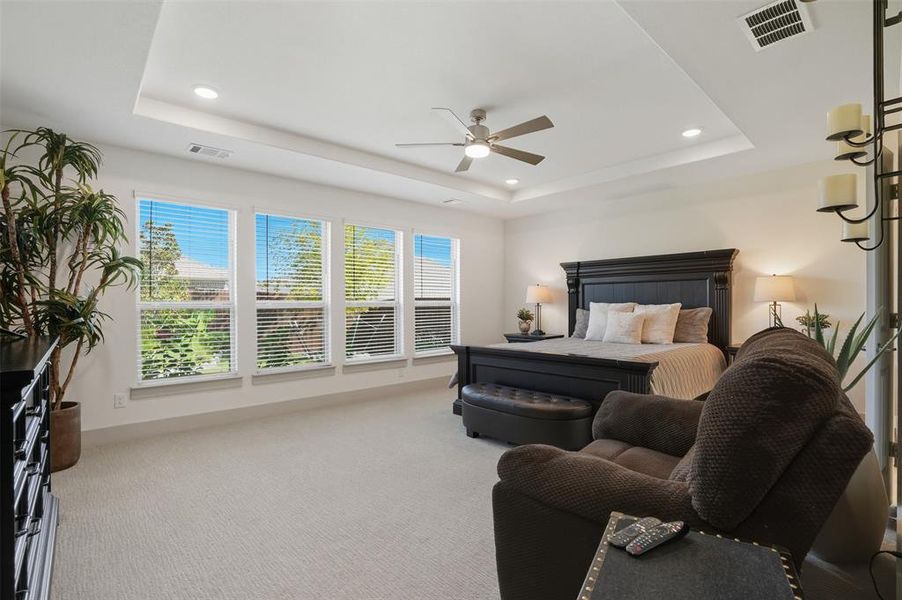 Carpeted bedroom featuring a raised ceiling, recessed lighting, and a ceiling fan Carpeted bedroom featuring a raised ceiling, recessed lighting, and a ceiling fan