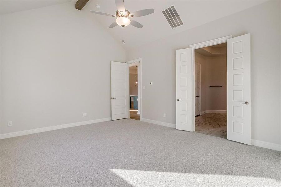 Unfurnished bedroom with carpet, ceiling fan, beam ceiling, and high vaulted ceiling