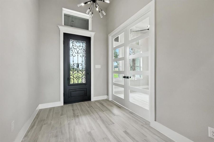 Entryway with french doors, a chandelier, and wood finished floors Entryway with french doors, a chandelier, and wood finished floors