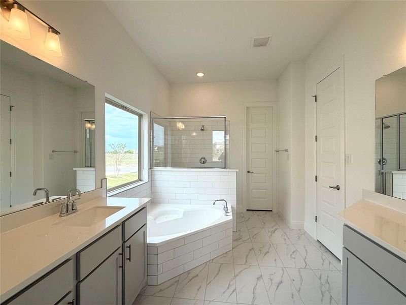 Bathroom featuring vanity, a garden tub, a shower stall, marble look tile flooring, and recessed lighting Bathroom featuring vanity, a garden tub, a shower stall, marble look tile flooring, and recessed lighting