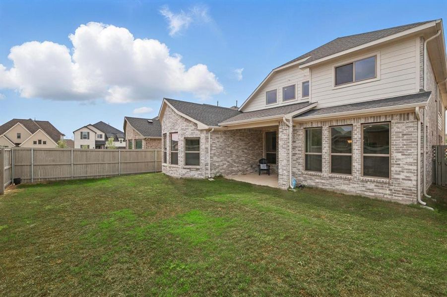Rear view of house with a patio area, a fenced backyard, brick siding, a residential view, and roof with shingles