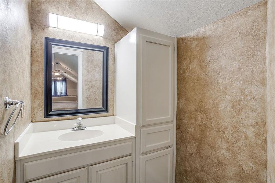 Bathroom with vanity, a textured ceiling, and vaulted ceiling Bathroom with vanity, a textured ceiling, and vaulted ceiling
