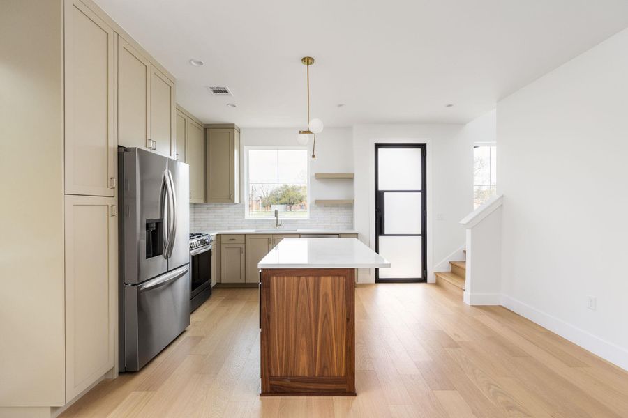 Kitchen featuring stainless steel appliances, a center island, light wood-type flooring, open shelves, and backsplash