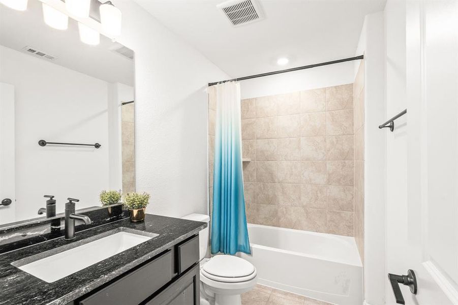 Full bathroom featuring vanity, shower / bath combo with shower curtain, and light tile patterned floors