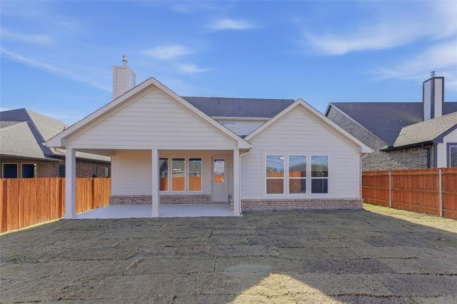 Rear view of house with a patio area, a fenced backyard, a chimney, and brick siding