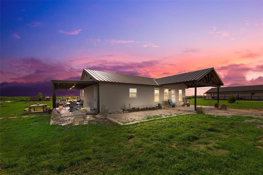 Back of property featuring a patio area, metal roof, and a lawn