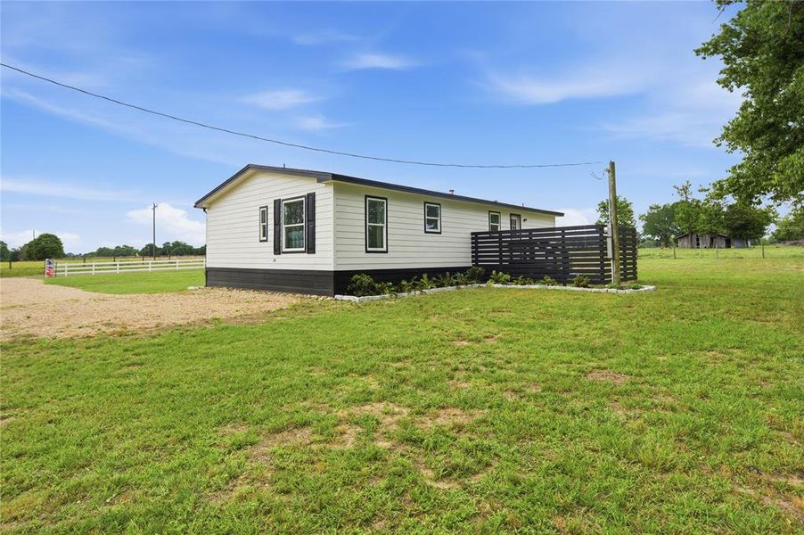 Contemporary single-story home featuring light-colored siding, dark trim, and a black horizontal slat privacy screen