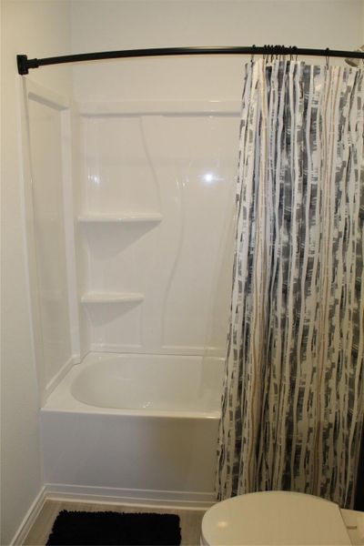 Bathroom with shower / tub combo with curtain and toilet