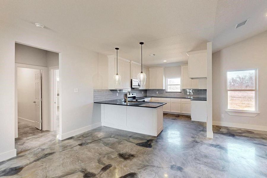 Kitchen with dark countertops, white microwave, tasteful backsplash, and stainless steel electric range