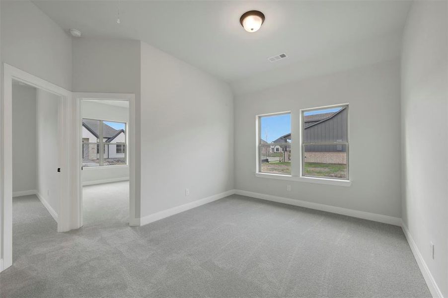 Empty room with light colored carpet, lofted ceiling, and plenty of natural light