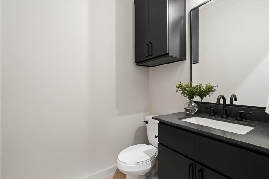 A well-appointed powder room features sleek black cabinetry, a coordinating countertop, and contemporary fixtures. A well-appointed powder room features sleek black cabinetry, a coordinating countertop, and contemporary fixtures.