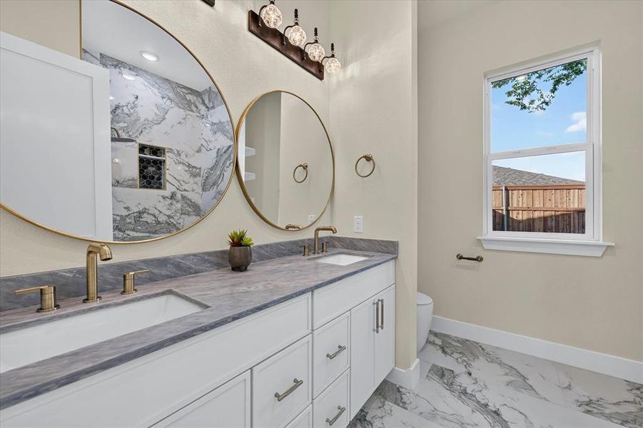 Dual vanity featuring under-mount sinks, gold-finish fixtures, and a gray stone countertop Dual vanity featuring under-mount sinks, gold-finish fixtures, and a gray stone countertop