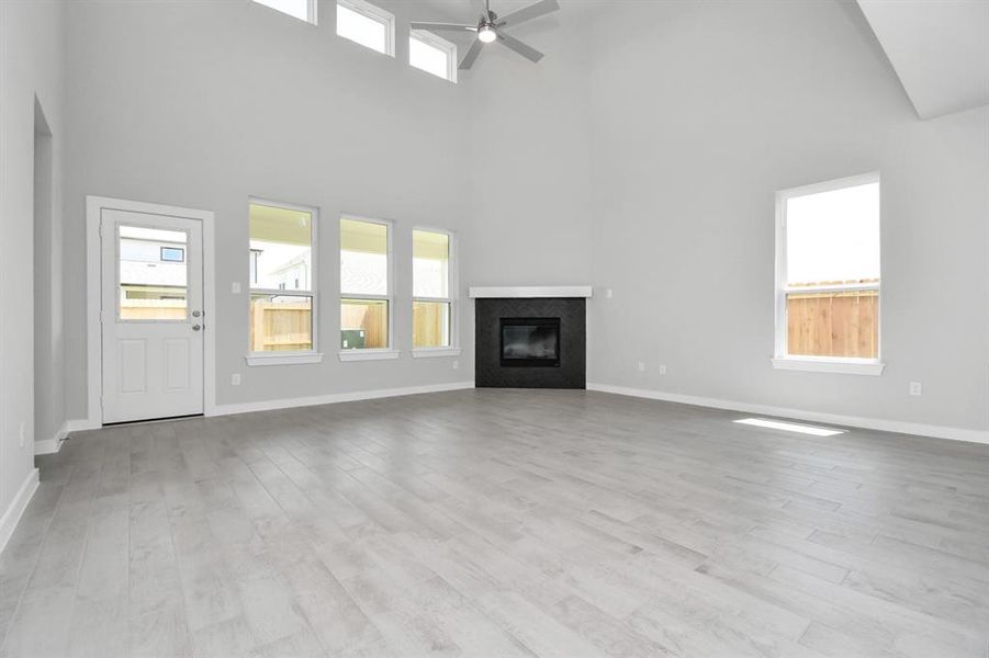 Family room flooded with natural light through the expansive windows.  The premium tile flooring adds a touch of luxury to the space, creating the perfect setting for relaxing moments and cherished gatherings with loved ones.  Sample photo of completed home with similar plan. As built color and selections may vary.