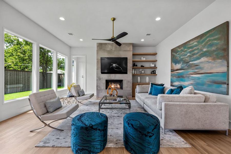 Living room featuring a tile fireplace, light wood-type flooring, and ceiling fan